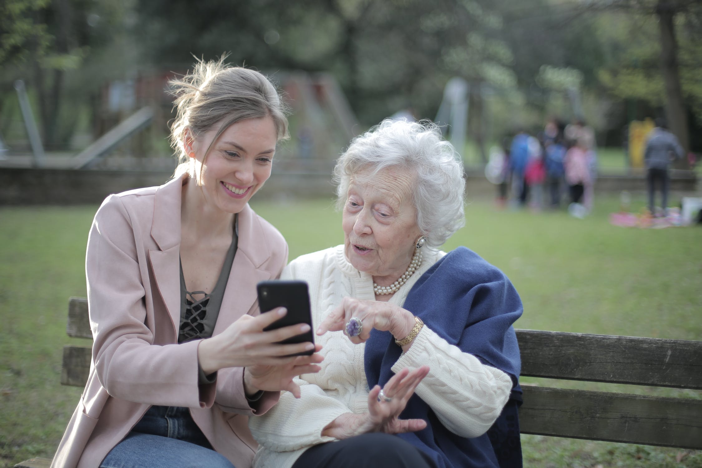 Middle age woman looking at a phone in the park with older woman